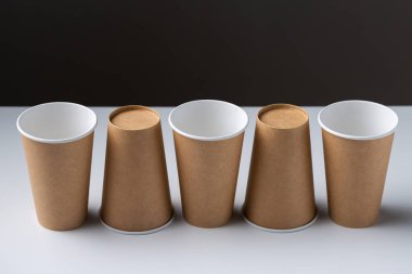 Disposable cardboard biodegradable cups on a white table, gray background.