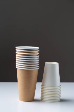 Disposable cardboard biodegradable cups on a white table, gray background.