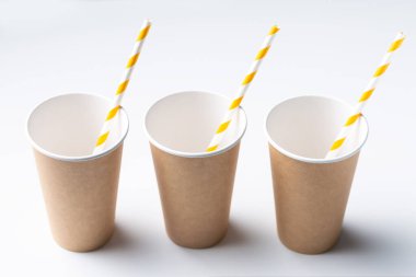 Disposable cardboard biodegradable cup on a white table with a straw.