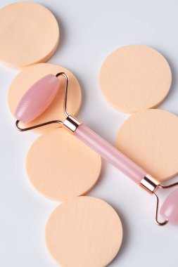Pink Gua Sha massage tool on a white background, close-up. Rose Quartz jade roller.