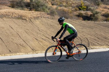 Cyclist riding bicycle on road against clear sky