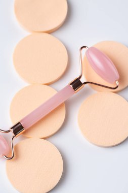 Pink Gua Sha massage tool on a white background, close-up. Rose Quartz jade roller.