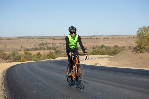 Cyclist riding bicycle on road against clear sky