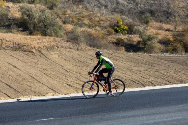 Cyclist riding bicycle on road against clear sky