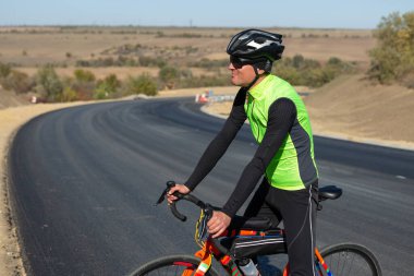 Cyclist riding bicycle on road against clear sky