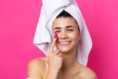 Beautiful cheerful attractive girl with a towel on her head, holds a sponge in the form of a pink heart.