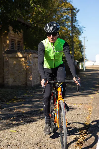 A man in clothes stands with a bicycle on an autumn sunny day. Cyclist in an urban environment.