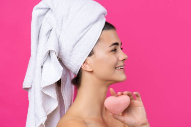 Kafasında havluyla güzel, çekici bir kız, pembe kalp şeklinde bir sünger tutuyor..