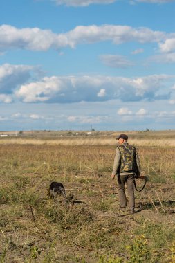 Mature man hunter with gun while walking on field.