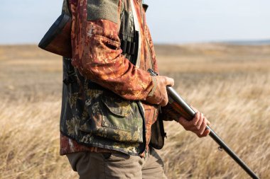 Midsection of man unloading shotgun while standing on field