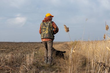 Mature man hunter with gun while walking on field.