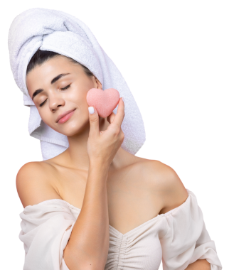 Beautiful cheerful attractive girl with a towel on her head, holds a sponge in the form of a pink heart.