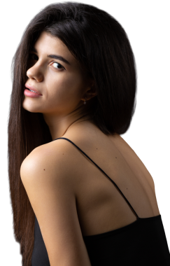 Classic studio portrait of a young brunette dressed in a black top, who is sitting on a chair against a black background.