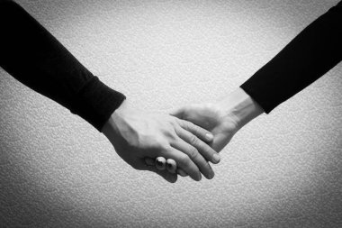 Black and white image of a handshake of man and woman on a gray background, black and white photo. Trust, love and be together