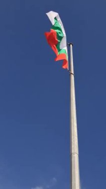 Bulgar bayrağı dalgalanırken, açık mavi gökyüzüne karşı beyaz-yeşil-kırmızı bayrak