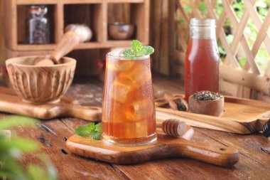 fresh cold tea with mint and ice cubes on wooden background