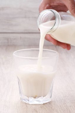 glass of milk and jug of white and tall fresh yogurt on a wooden background