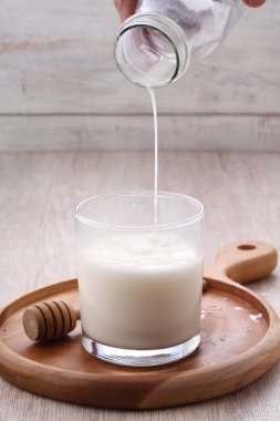 glass of milk with yogurt and fresh ingredients on wooden table