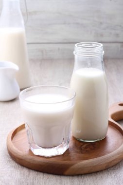 glass of milk and jug of white and fresh homemade yogurt on wooden table