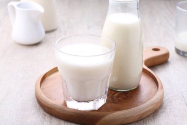 glass of milk and jug of white and fresh ripe delicious yogurt on wooden table