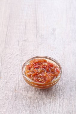 red pepper sauce in a glass bowl on a wooden white background