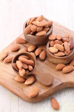 Hafif arka planda, tahtadan bir kasede badem.