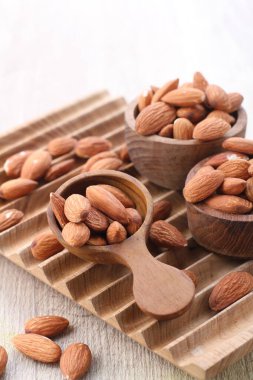 Hafif arka planda, tahtadan bir kasede badem.