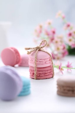 pink macaroons with a bouquet of white and blue flowers on a light background.
