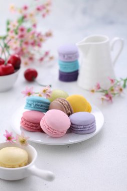 colorful macaroons and cup of tea on white table