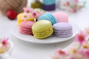 colorful macaroons with flowers on white background