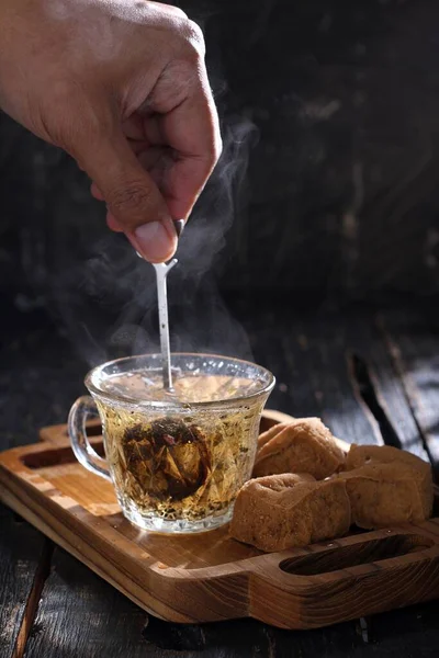 hand with a cup of tea and a glass of milk on a wooden background