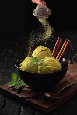 homemade lemon ice cream in a bowl on a black background.