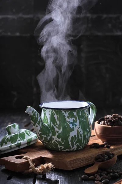 black coffee cup with tea and green leaves on wooden background