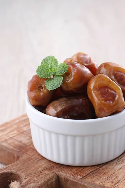 sweet dates in a bowl on a wooden background