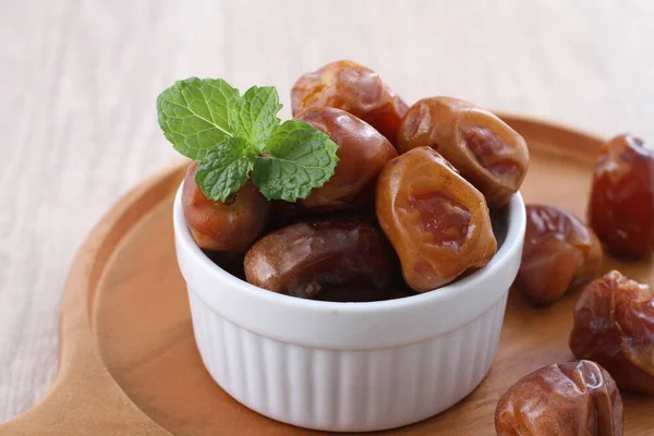 sweet dates in a bowl on wooden background