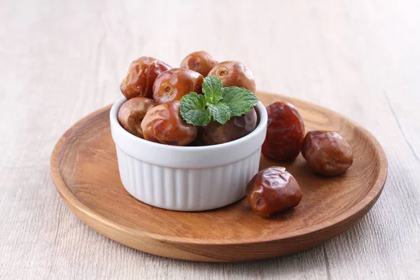 sweet dates in a bowl on wooden background