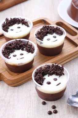 chocolate mousse with coffee beans and cinnamon sticks on a wooden background.