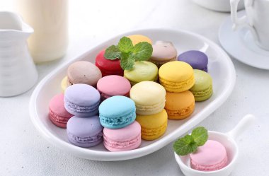 colorful macaroons with mint leaves on white background