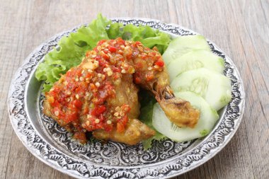 Ayam penyet  is Indonesian fried chicken dish consisting of fried chicken that is smashed with the pestle against mortar to make it softer, served with sambal, slices of cucumbers, fried tofu and tempeh.