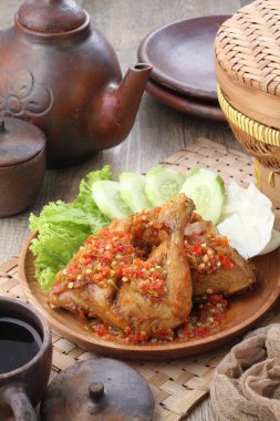 Ayam penyet  is Indonesian fried chicken dish consisting of fried chicken that is smashed with the pestle against mortar to make it softer, served with sambal, slices of cucumbers, fried tofu and tempeh.