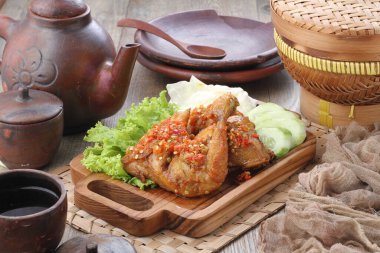 Ayam penyet  is Indonesian fried chicken dish consisting of fried chicken that is smashed with the pestle against mortar to make it softer, served with sambal, slices of cucumbers, fried tofu and tempeh.
