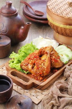 Ayam penyet  is Indonesian fried chicken dish consisting of fried chicken that is smashed with the pestle against mortar to make it softer, served with sambal, slices of cucumbers, fried tofu and tempeh.