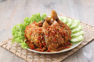 Ayam penyet  is Indonesian fried chicken dish consisting of fried chicken that is smashed with the pestle against mortar to make it softer, served with sambal, slices of cucumbers, fried tofu and tempeh.