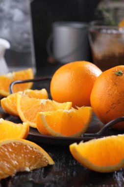 fresh orange and green tangerines with slices of oranges on a wooden table.