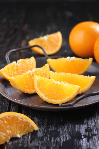 sliced oranges with slices, on a black wooden background, close up