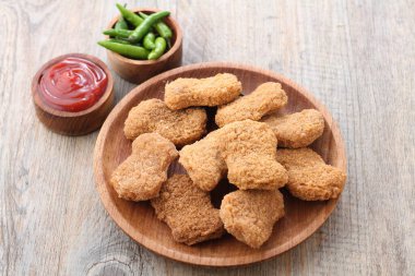 Soslu kızarmış tavuk nugget ve ahşap arka planda ketçap.