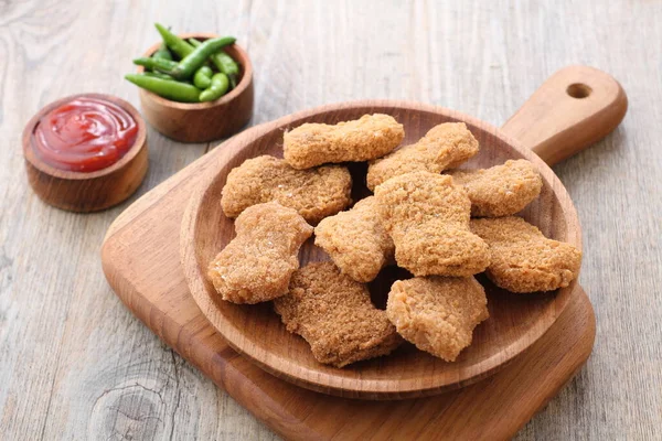 Soslu kızarmış tavuk nugget ve ahşap arka planda ketçap.