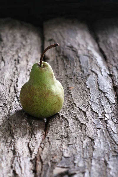 树皮后面的一个绿色梨子 — 图库照片