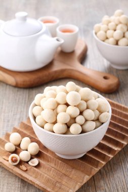 Tahta zemin üzerinde susam tohumları olan bir kase beyaz pirinç.