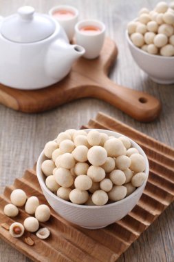 Tahta zemin üzerinde susam tohumları olan bir kase beyaz pirinç.